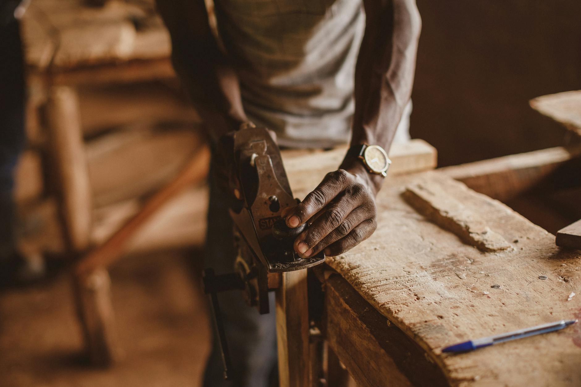Craftsman carefully sanding a large wooden dining table